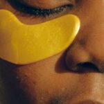 Patch Leaks - Crop gentle African American female with closed eyes and clean face enjoying cosmetic procedure for smoothing and moisturizing skin under eyes and removing dark circles