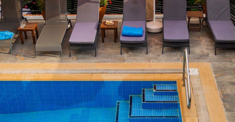 Pool Maintenance - A pool with umbrellas and lounge chairs next to a building