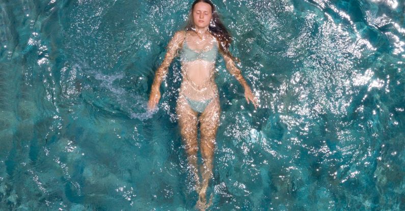 Seasonal Pool Closing - From above of young woman in bikini floating on azure calm sea water while enjoying vacation on resort