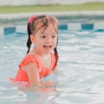 Pool Alarms - A little girl in an orange swimsuit in a pool