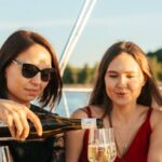 Foods And Drinks - A Woman Wearing Sunglasses Pouring a Drink while Talking to Her Friend