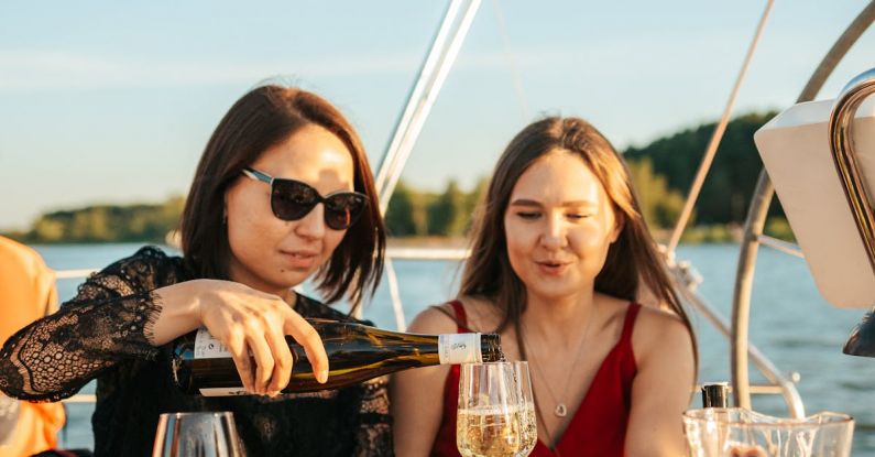 Foods And Drinks - A Woman Wearing Sunglasses Pouring a Drink while Talking to Her Friend